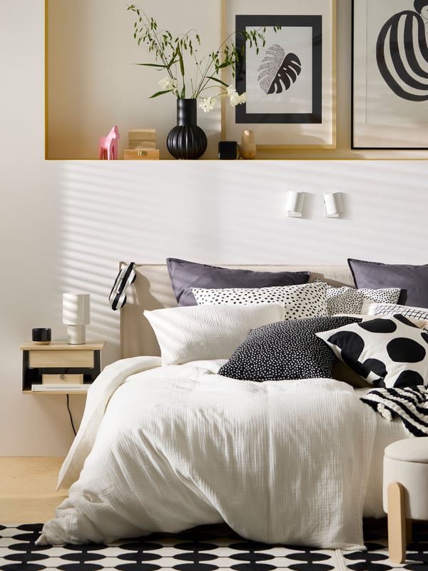 Es ist ein grosses Bett mit vielen Kissen und Bettzeug in weisser SCHERSMIN Bettwäsche aus Bio-Baumwolle zu sehen.