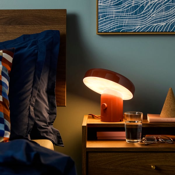 A red/brown BLOMPRAKT Bluetooth speaker lamp in the bedroom