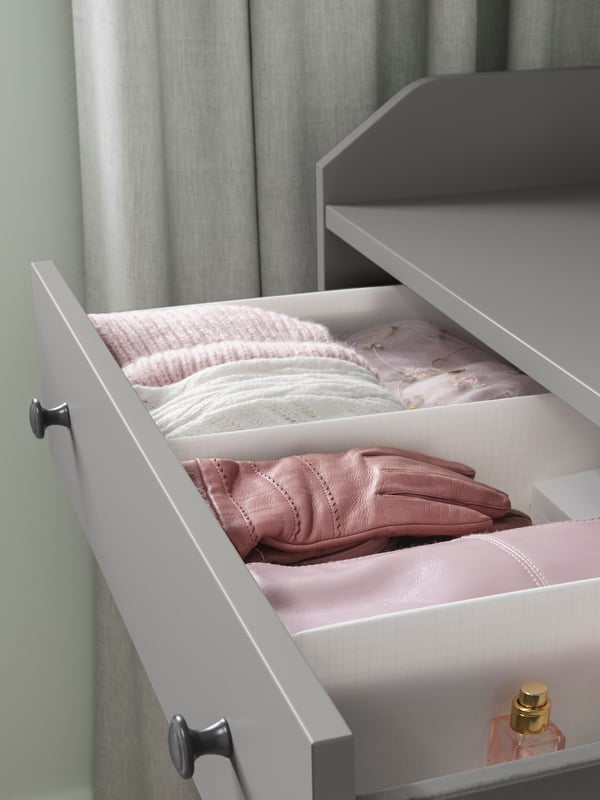 Gants en cuir rose et autres accessoires roses dans un rangement à compartiments STUK blanc logé dans une commode HAUGA grise.