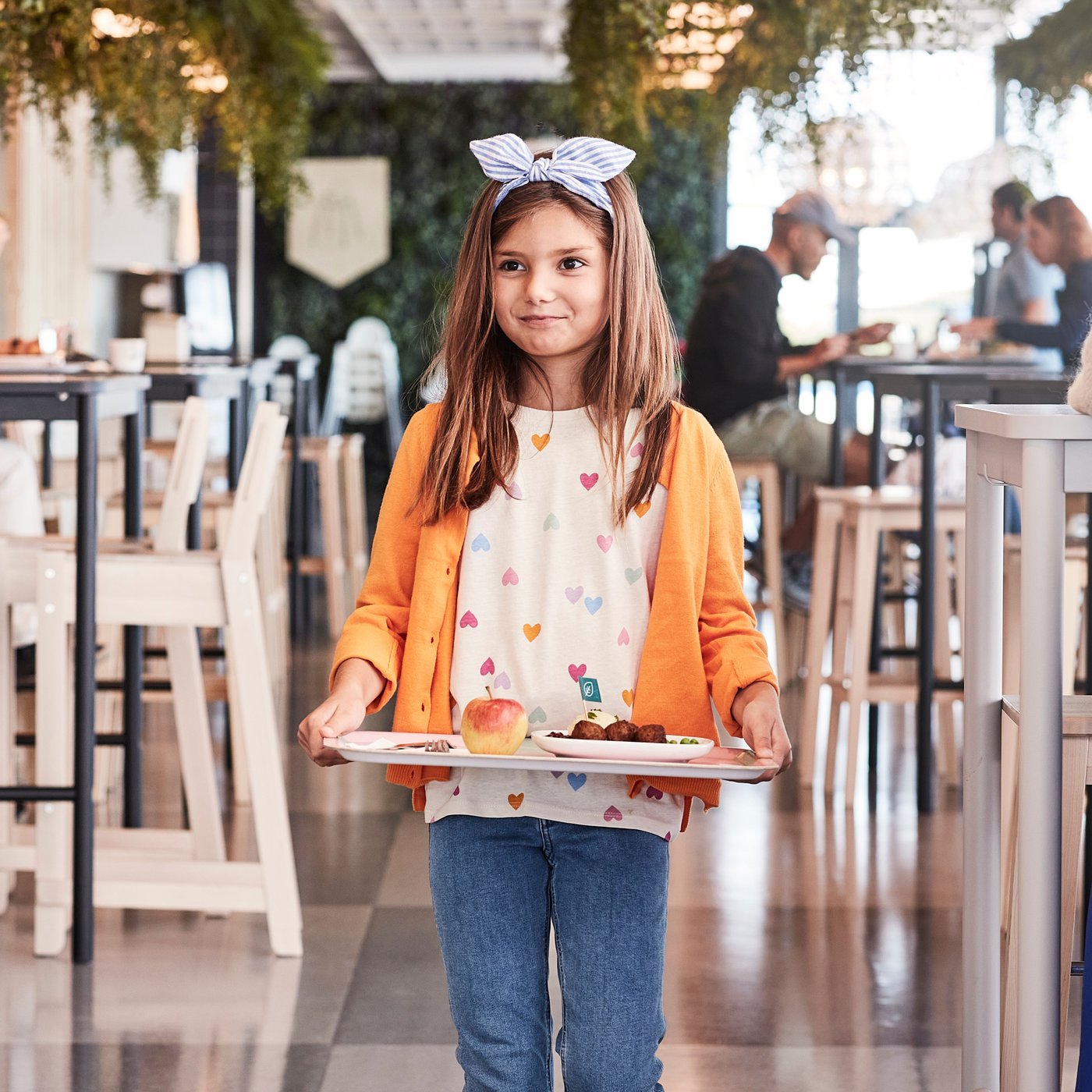 Jeune fille tenant un plateau de nourriture dans le restaurant IKEA.