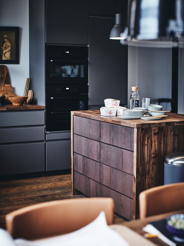 A SEKTION kitchen with a wooden kitchen island with plates and takeaway food containers on top.