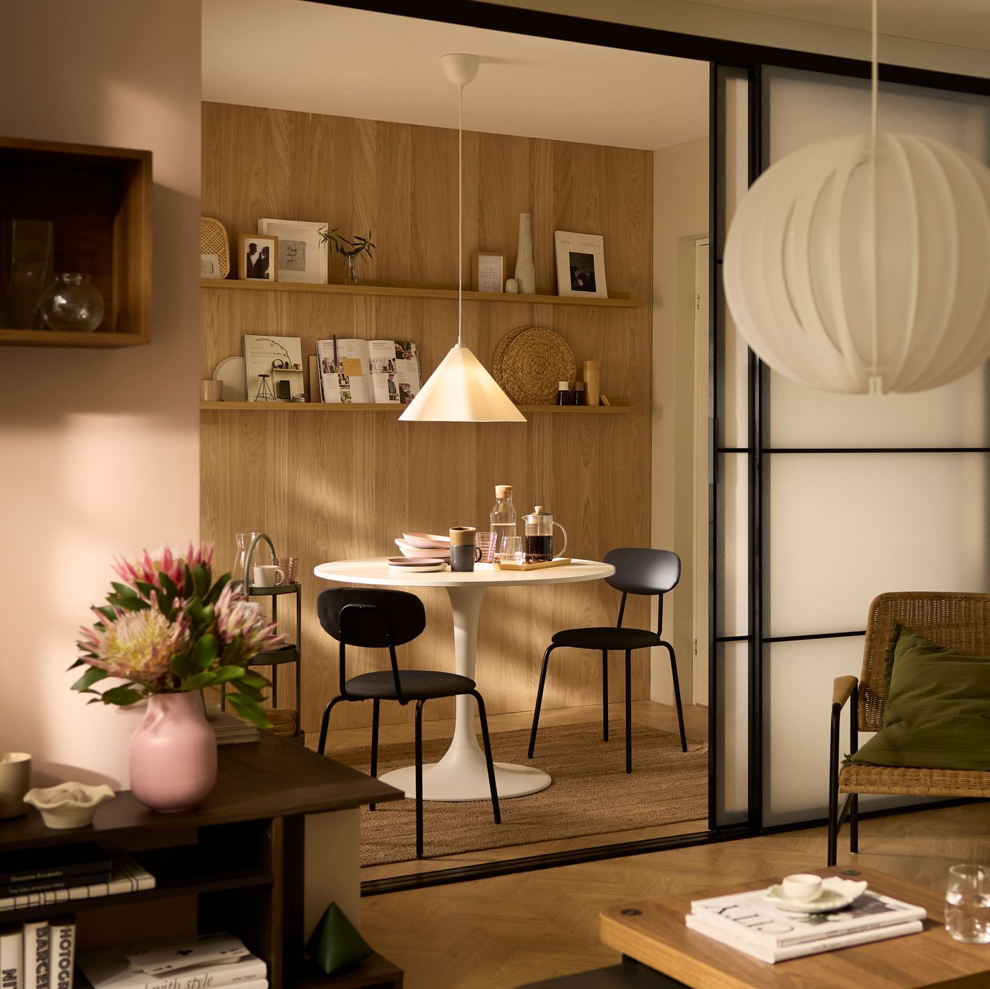 A sunlit living room opening up, by way of a pair of SKYTTA sliding doors, onto a dining alcove with a round DOCKSTA table.