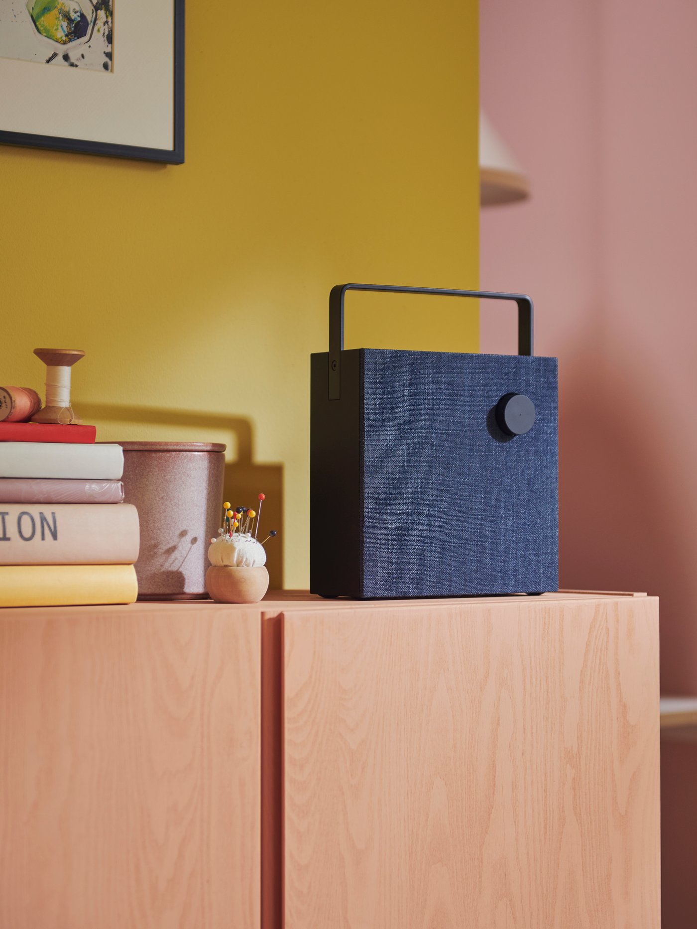 Two VAPPEBY speakers, one in white, one in black on two yellow stands with a yellow background.