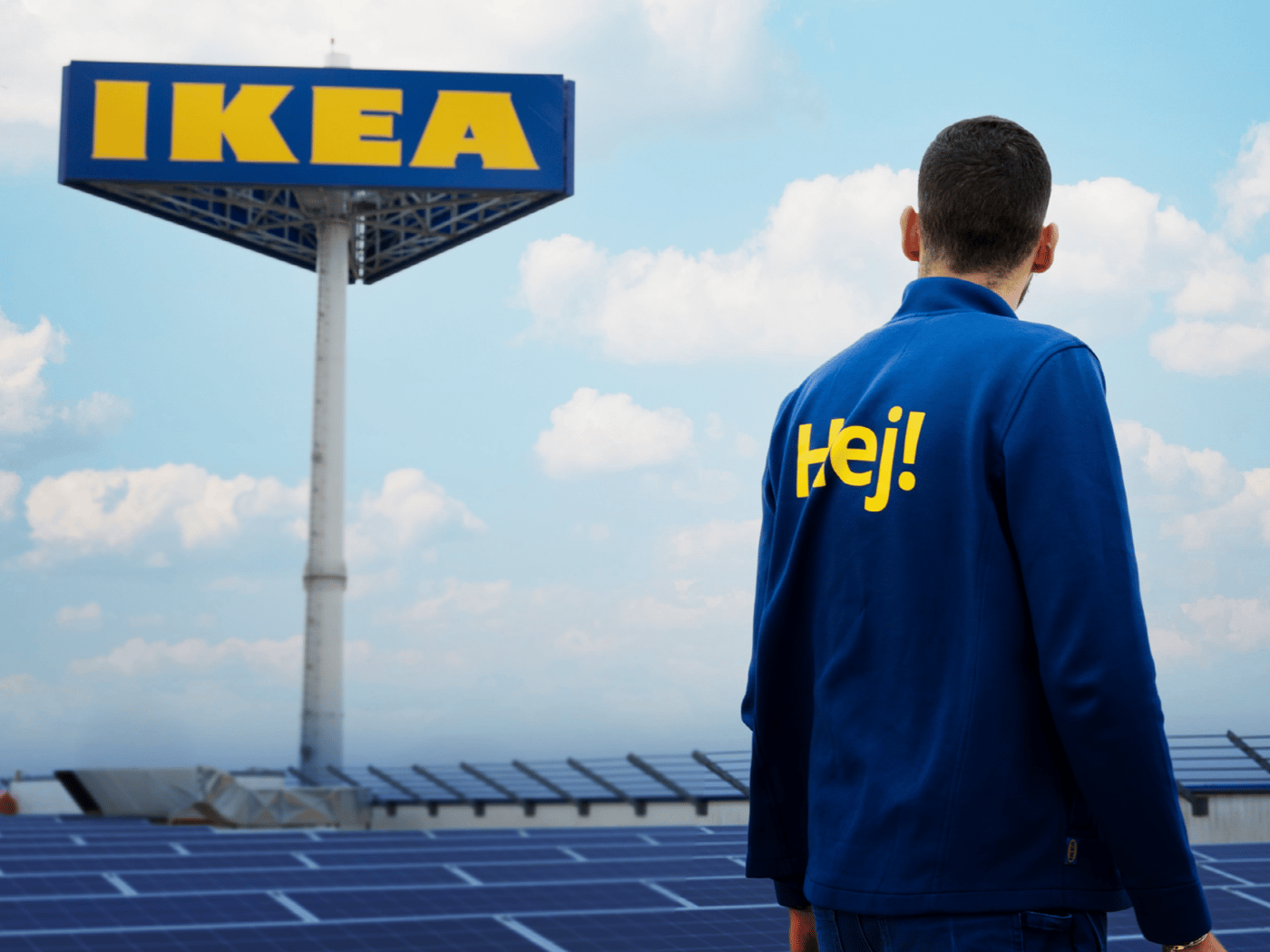 A co-worker stands in front of an IKEA sign, surrounded by solar panels under a clear sky.