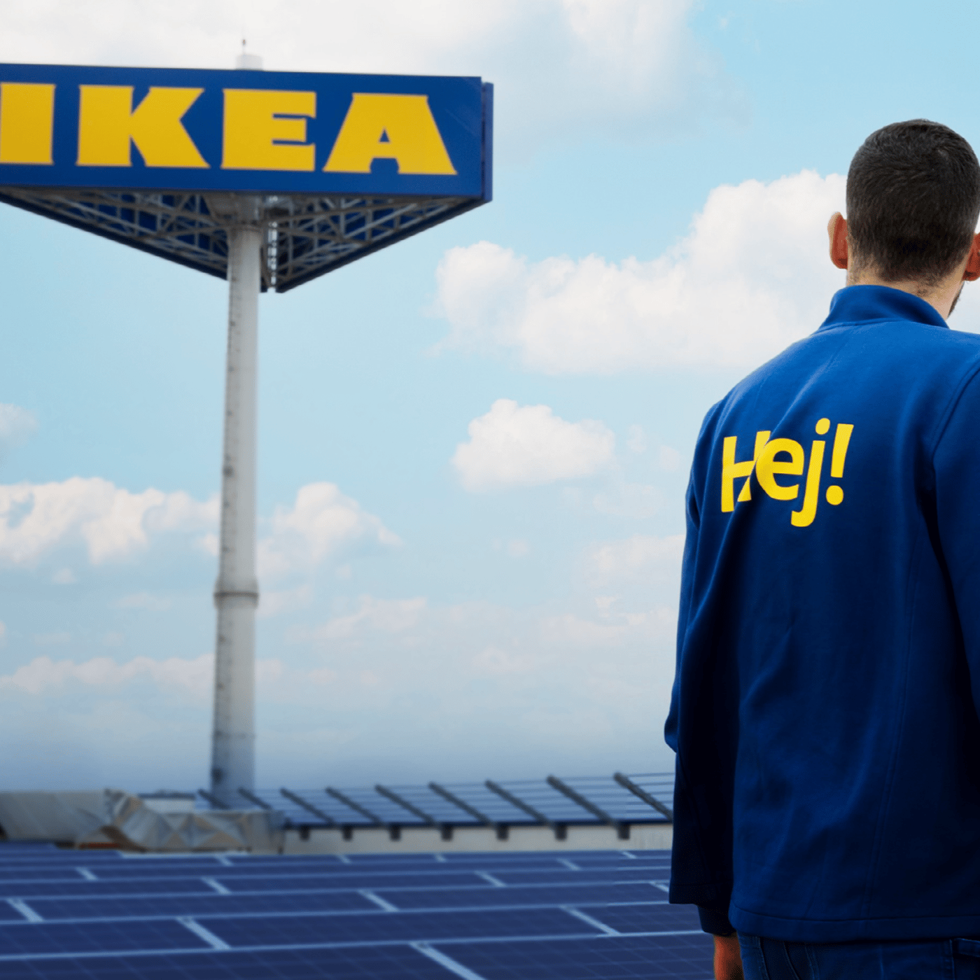 Zaposleni stoji ispred IKEA znaka, okruženog solarnim panelima pod vedrim nebom