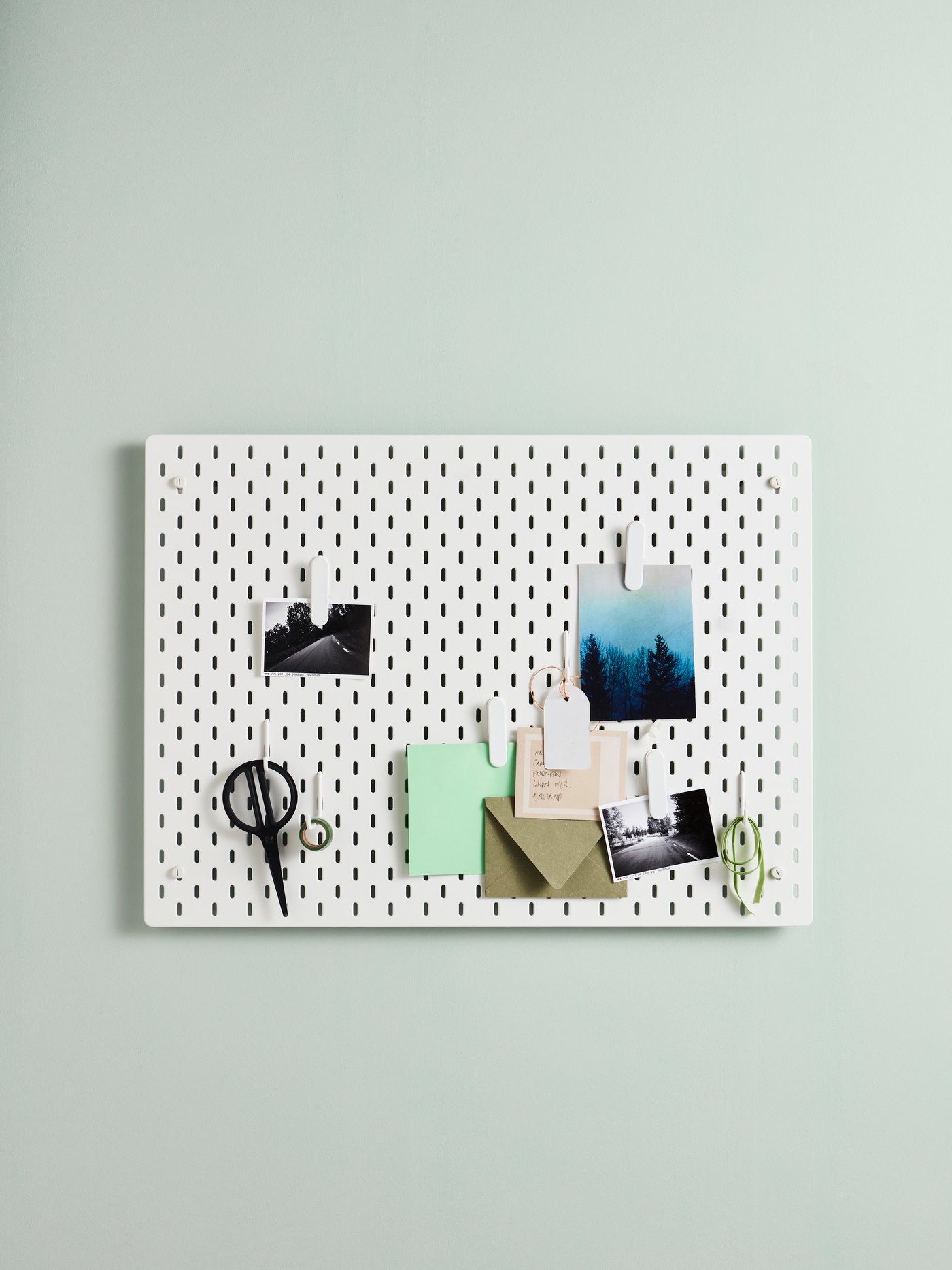 Una pared con un tablero de organización. En el tablero hay fotos colgadas, unos papeles y un lápiz.