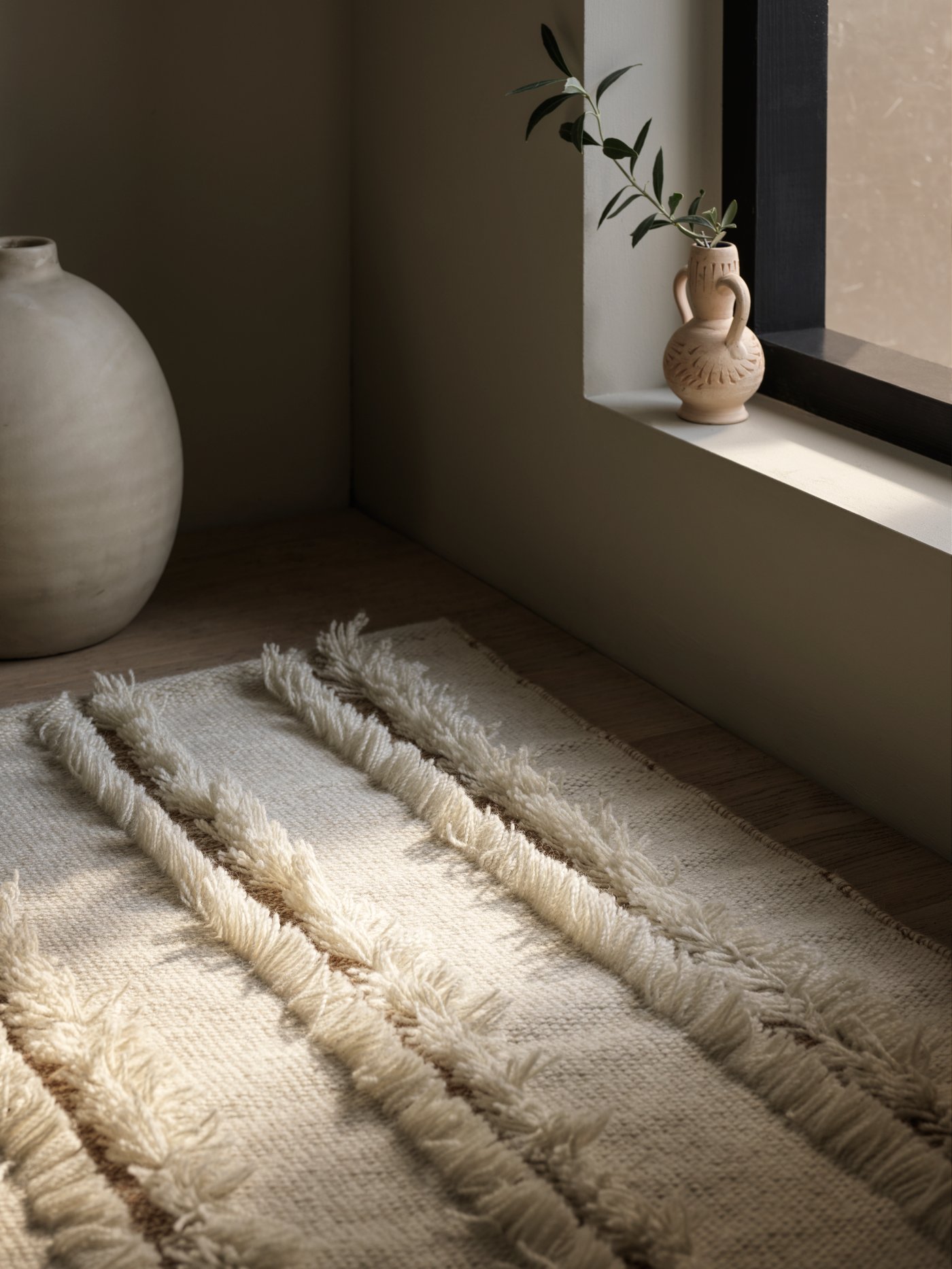 A natural/off-white PEDERSBORG flatwoven rug lies on the floor in front of a window with the blind pulled down.