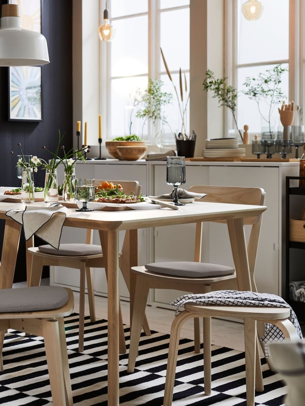 Una mesa de comedor LISABO rodeada de pisos apilables KYRRE.
