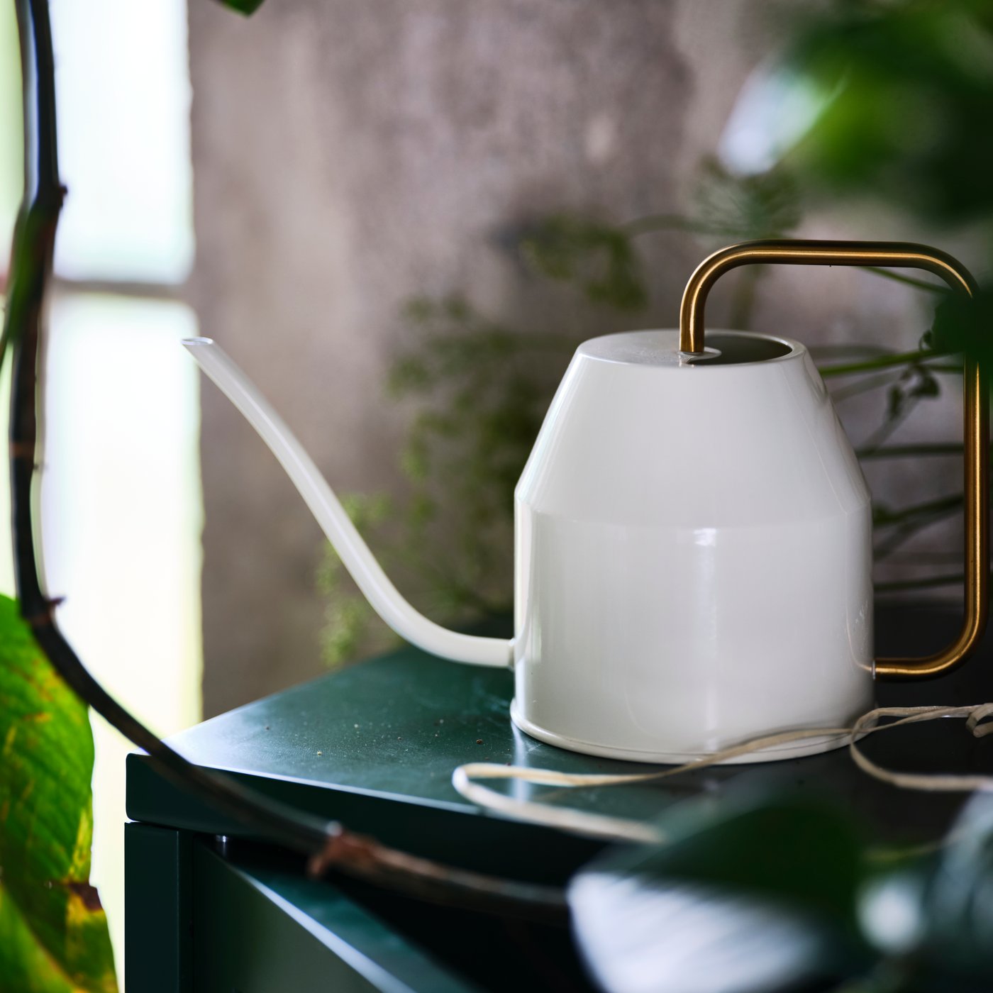 An ivory/gold-colour VATTENKRASSE watering can outside