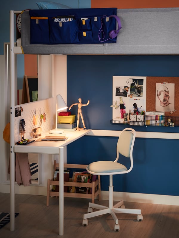 A white FUBBLA work lamp brightens up a desk and an ÖRFJÄLL children’s desk chair underneath a VITVAL loft bed.