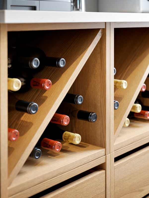 Two VADHOLMA wine shelves in stained ash with wine bottles inside.
