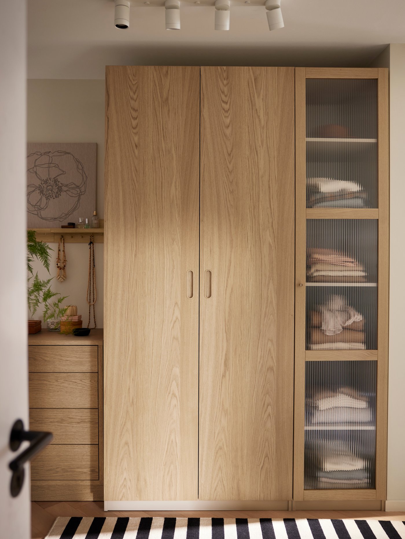 An oak veneer TONSTAD chest of 4 drawers stands beside a PAX/TONSTAD wardrobe with two oak veneer doors and one glass door.