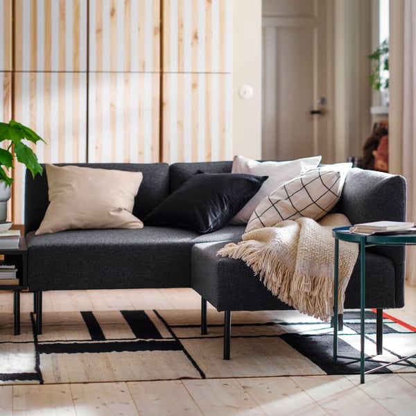 Some extra cushions and a LAPPTÅG throw lie on a LILLEHEM modular corner sofa with dark grey covers.