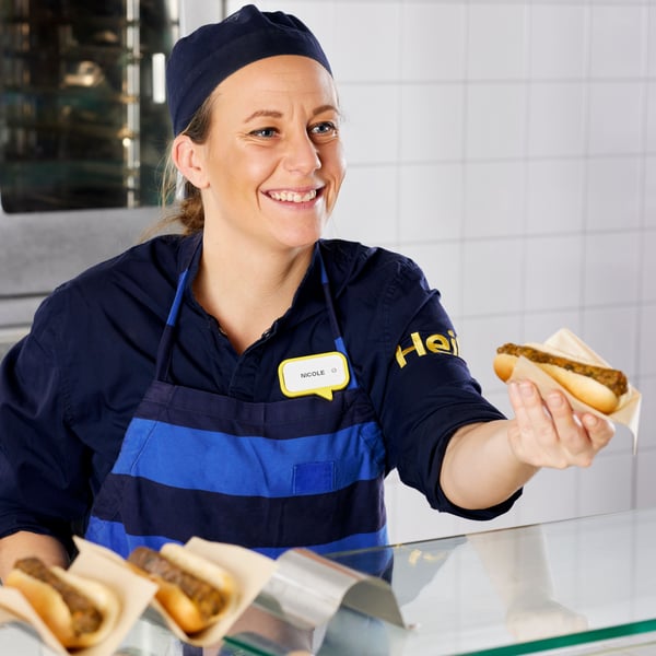 An IKEA Food co-worker serving a hot-dog to a customer
