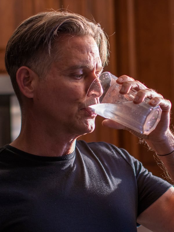 A man drinks lemon water from a POKAL glass.