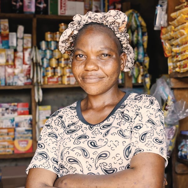 A person standing in a store with arms crossed looking into the camera. 