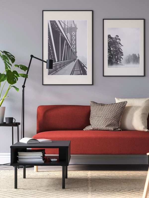Red LILLEHEM two-seat sofa in the living room next to a floor lamp and GLADOM black table. 