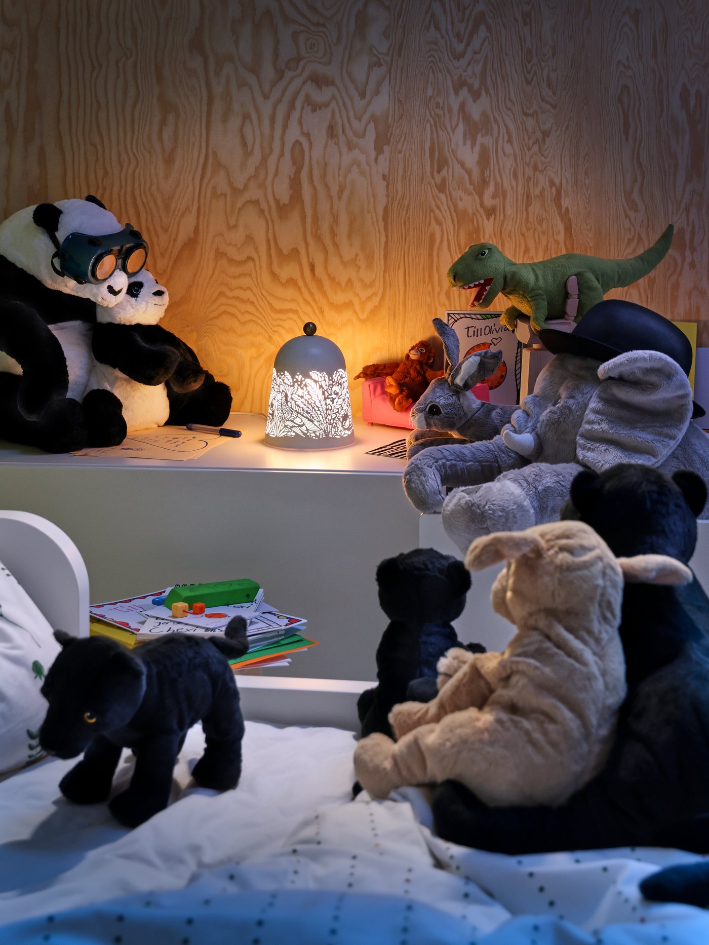 Soft toys surround a lamp at night.