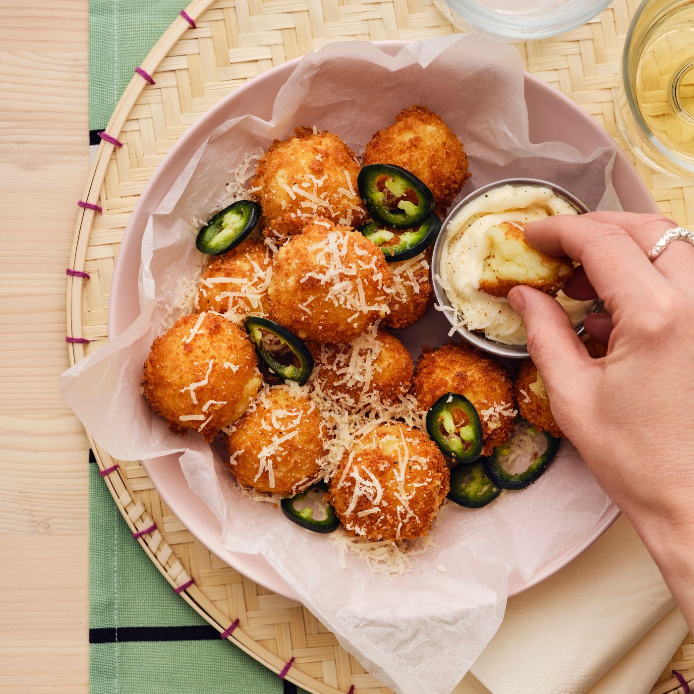 A person’s hand dips a croquette from a serving made from ALLEMANSRÄTTEN mashed potatoes into a creamy sauce.