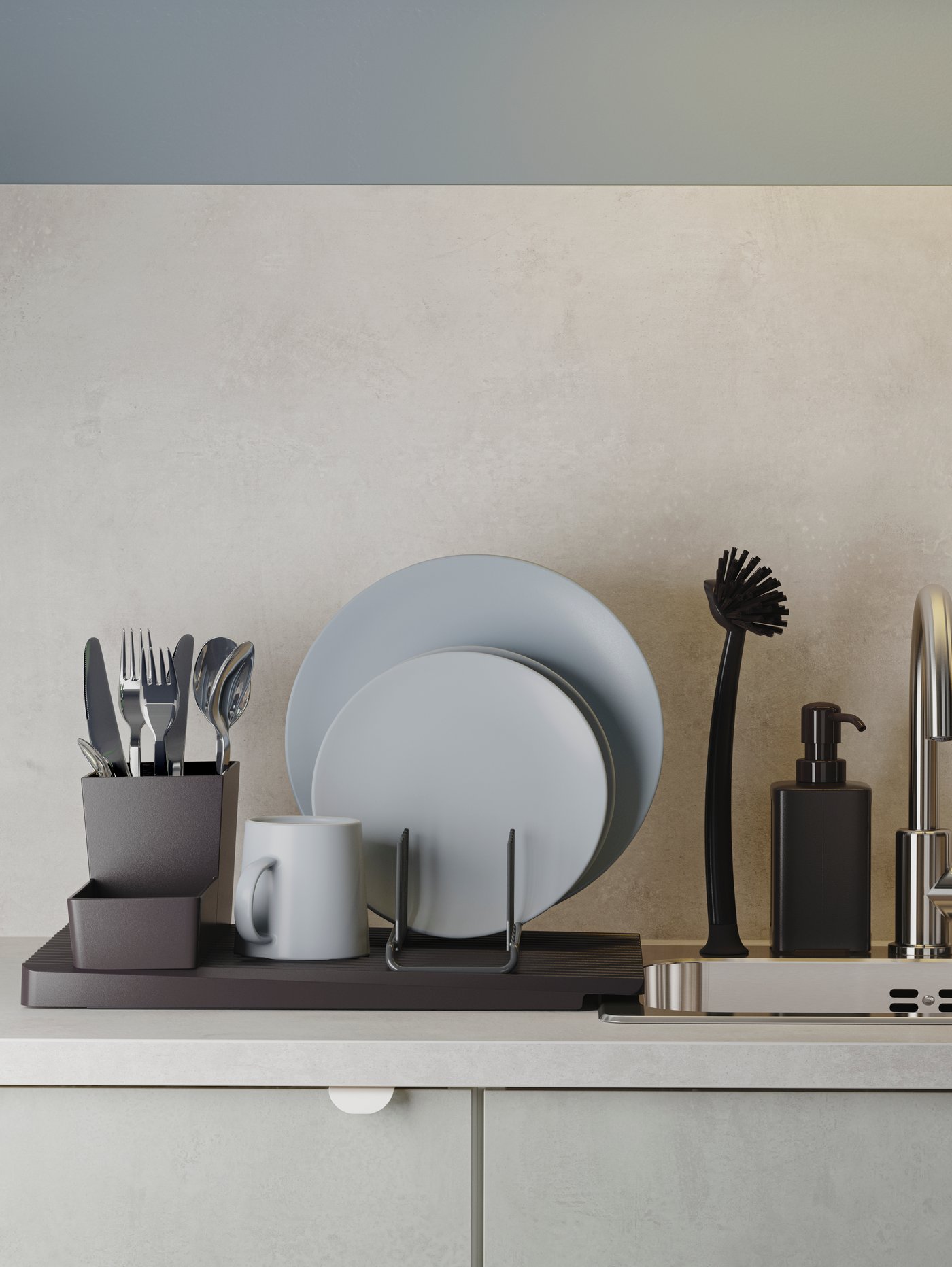 A black dish drainer with grey-blue dinnerware and cutlery stands next to an inset sink in stainless steel.