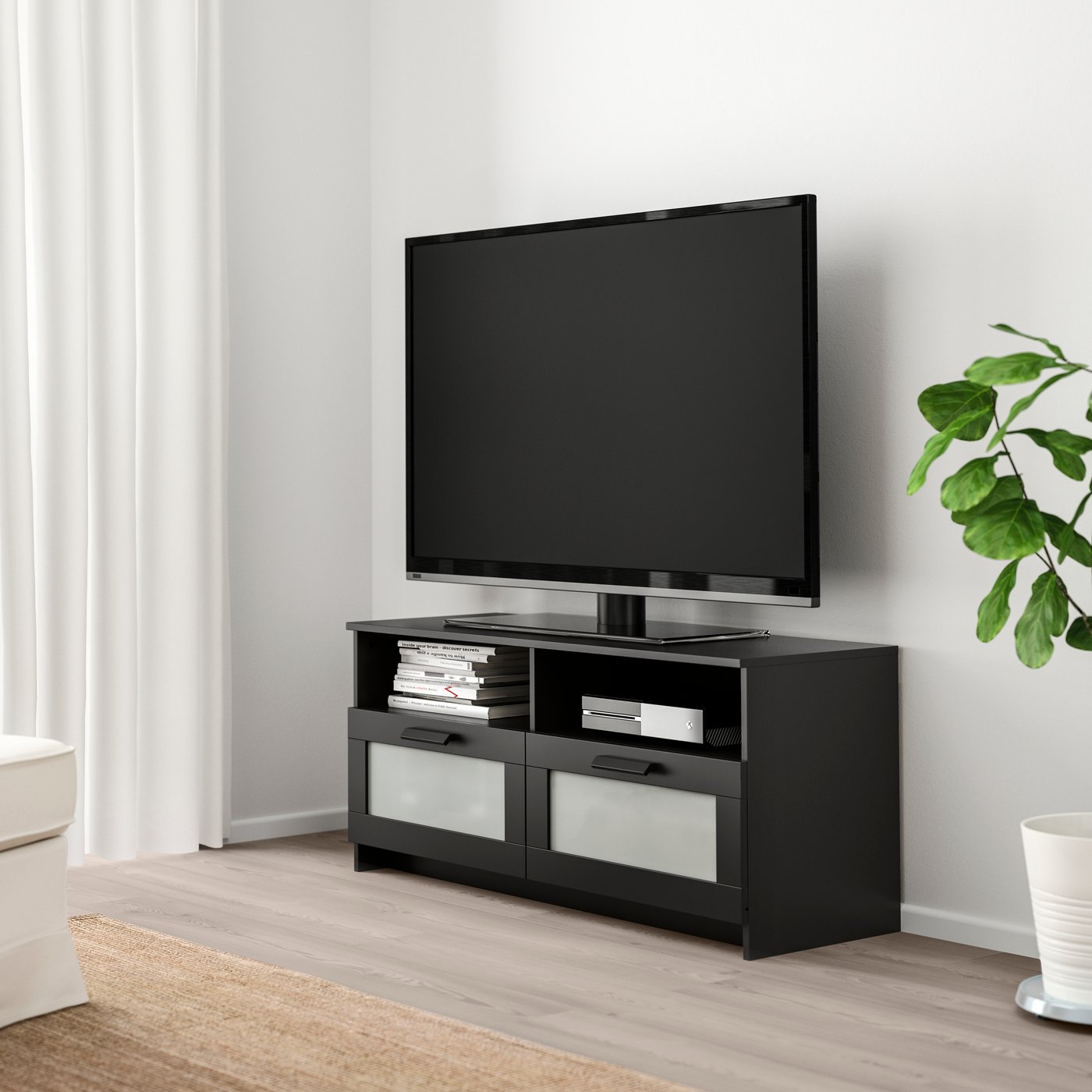 En liten svart tv-bänk med lådor i ljust rum.