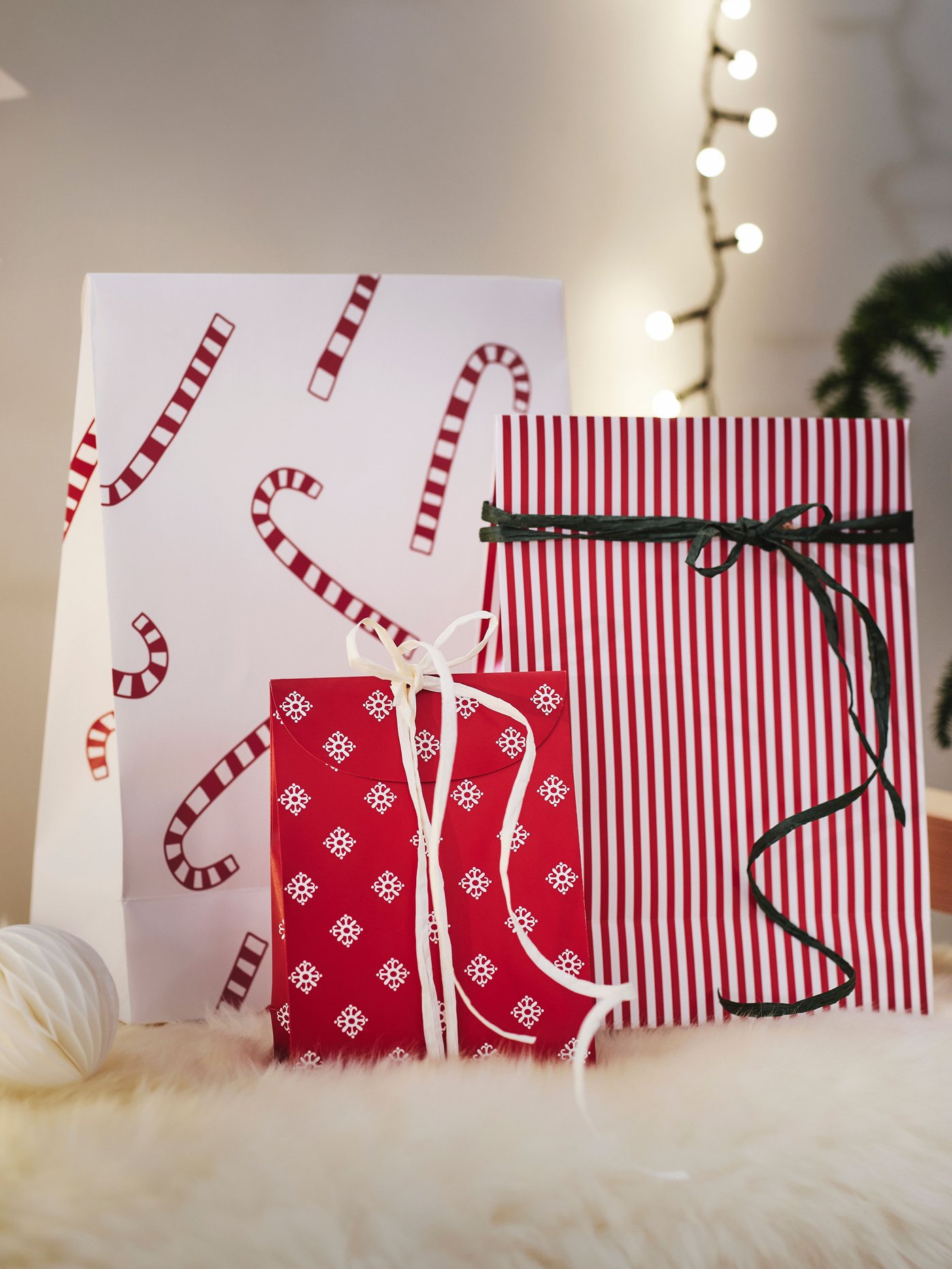 En samling af VINTERFINT gaveposer med forskellige motiver på. En gavepose har smalle røde og hvide striber og et sort bånd omkring. En gavepose er rød med print af små snefnug på og et hvidt bånd mens den tredje gavepose er hvid med et print af julestokke på.