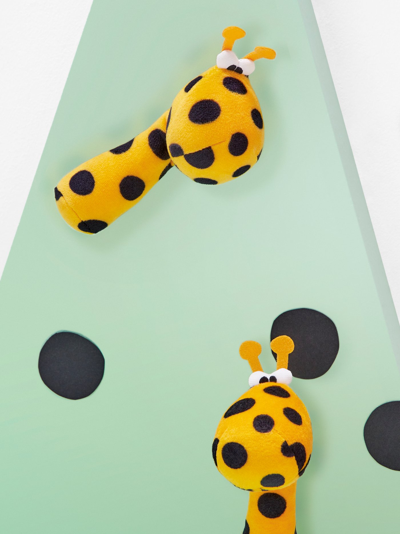 Un hochet KLAPPA jaune posé sur une surface vert pâle.