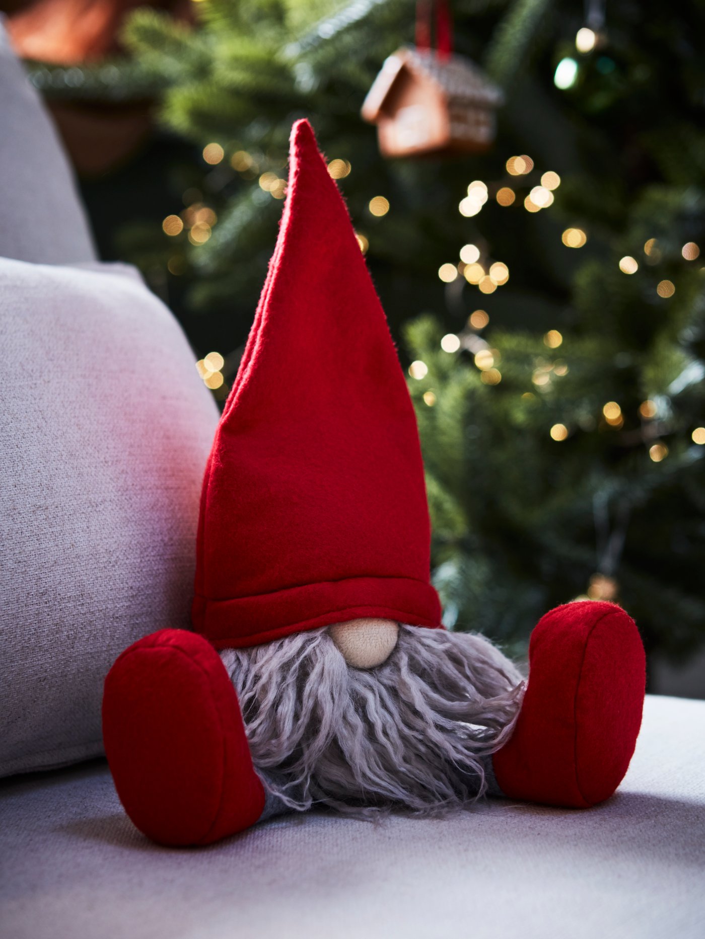 A red and grey VINTERFINT Santa Claus decoration sits on a white chair. A decorated Christmas tree is behind it.