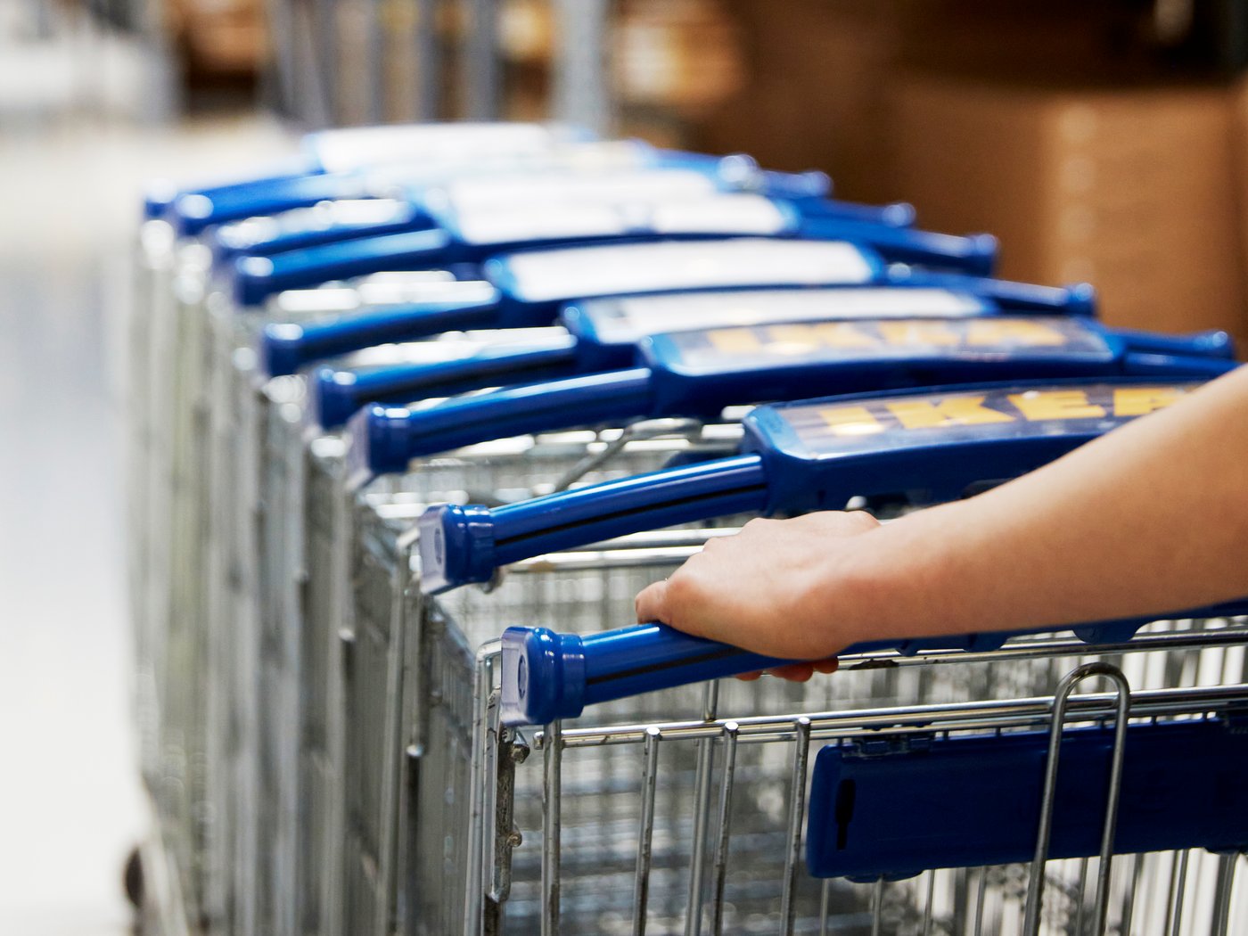 A stack of IKEA shopping trolleys being pushed through an IKEA store.