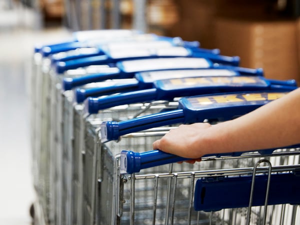 IKEA medarbejder skubber en stabel rullevogne igennem et IKEA varehus.