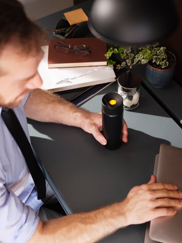 UNDERSÖKA insulated steel flask on the hand of a man working on his desk.