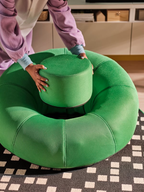 A person’s hands lifting out the inner cushion of a BRÄNNBOLL inflatable gaming lounge chair in bright green.