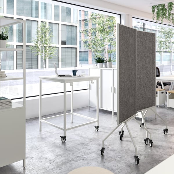 A bright office with white furniture and plants.