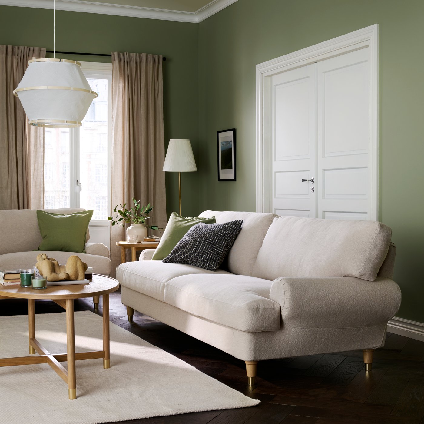 A living room with a light beige VALNÄS 3-seat sofa made from Knäbäck, accompanied by soft cushions and a coffee table.