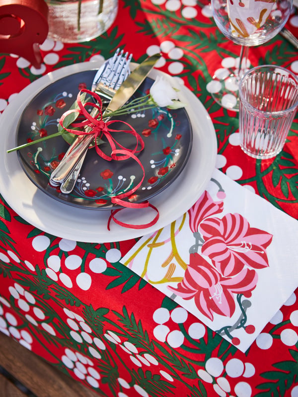 Una mesa navideña con un mantel VINTERFINT, vajillas y servilletas con dibujos de Navidad.