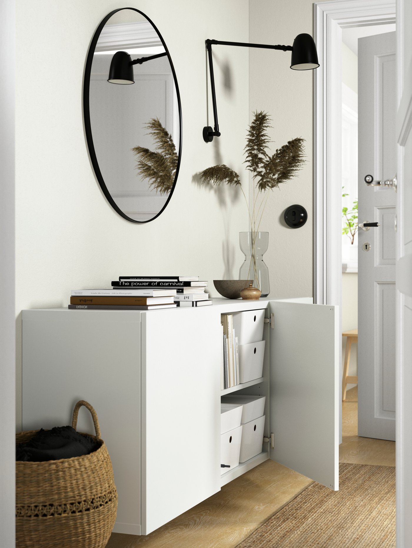 A white cabinet with a round mirror above it and plant beside it
