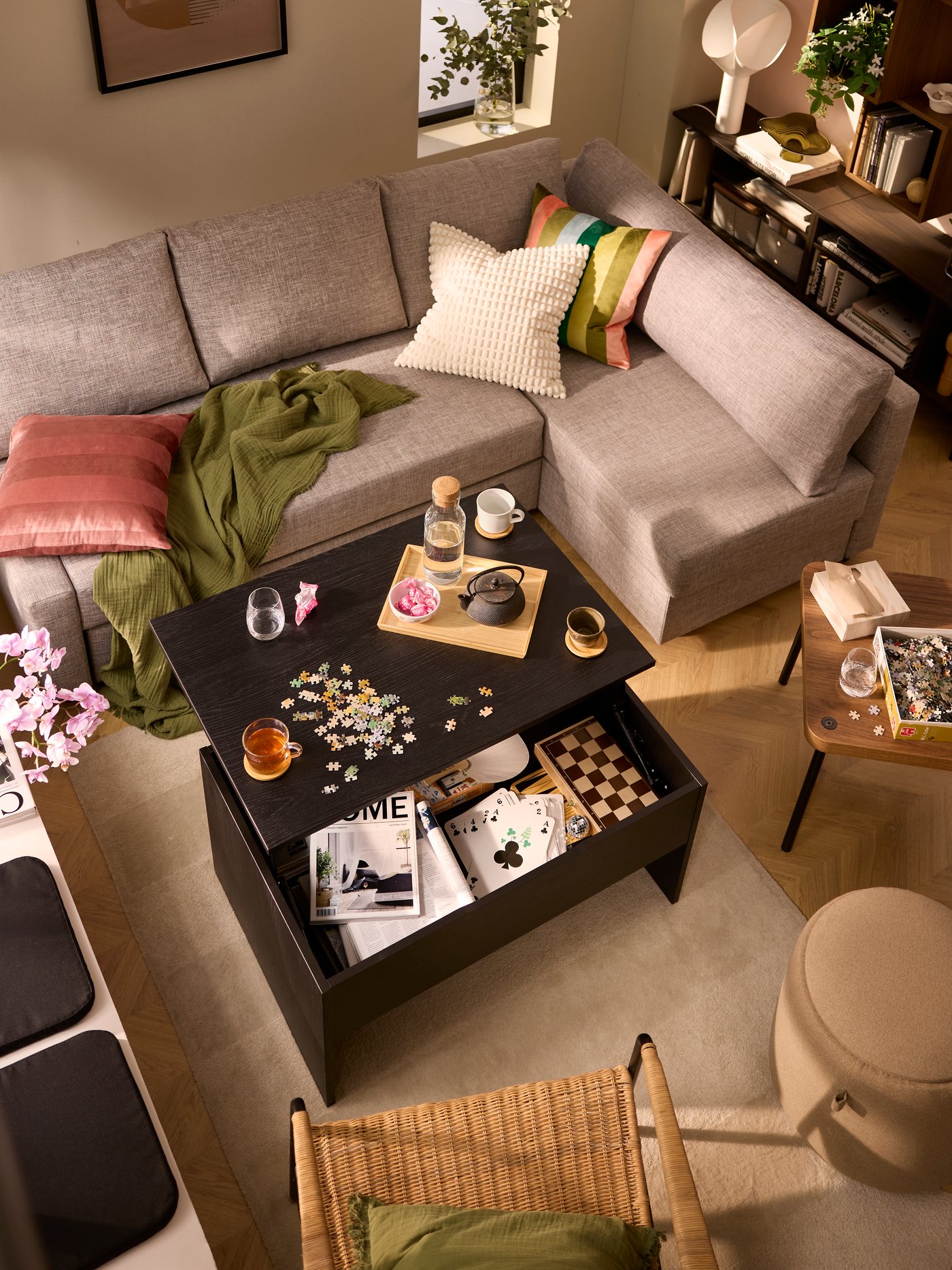 A living room where a sofa, an ULRIKSBERG armchair and other seating surround a black ÖSTAVALL adjustable coffee table.