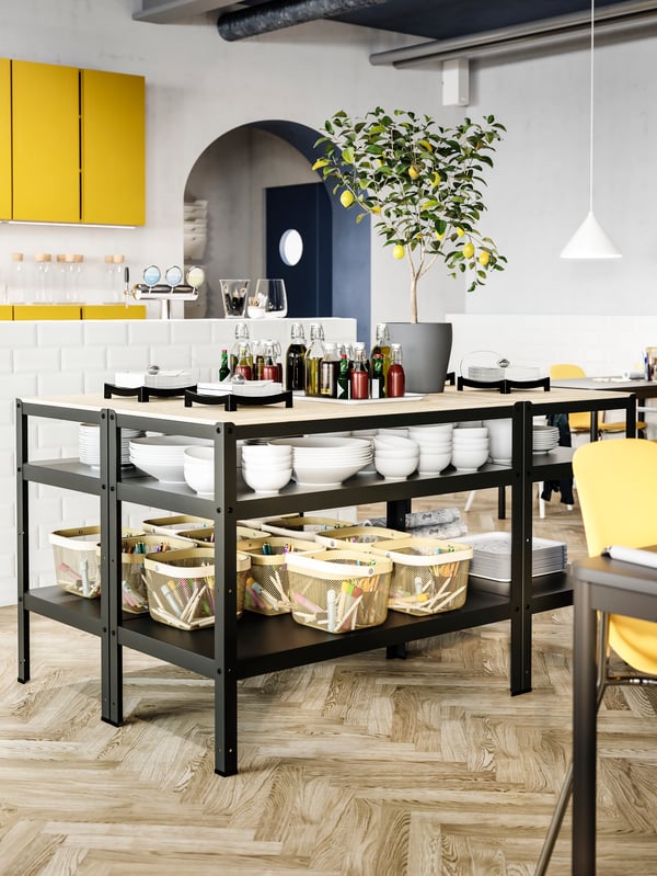 Black work benches with wooden table tops, white bowls, light olive-green baskets with coloring supplies and condiments.