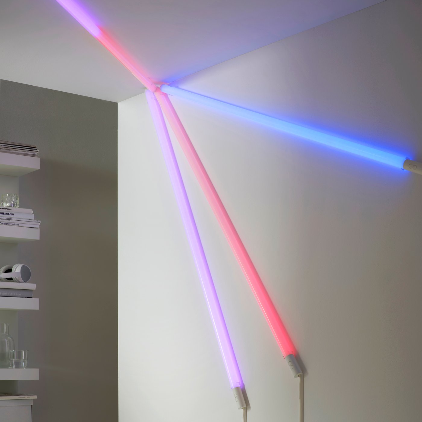 Četiri FÖRLIG LED podne/zidne lampe montirane zajedno u određeni oblik na zidu i plafonu, pri čemu svaka svetli u različitoj boji.