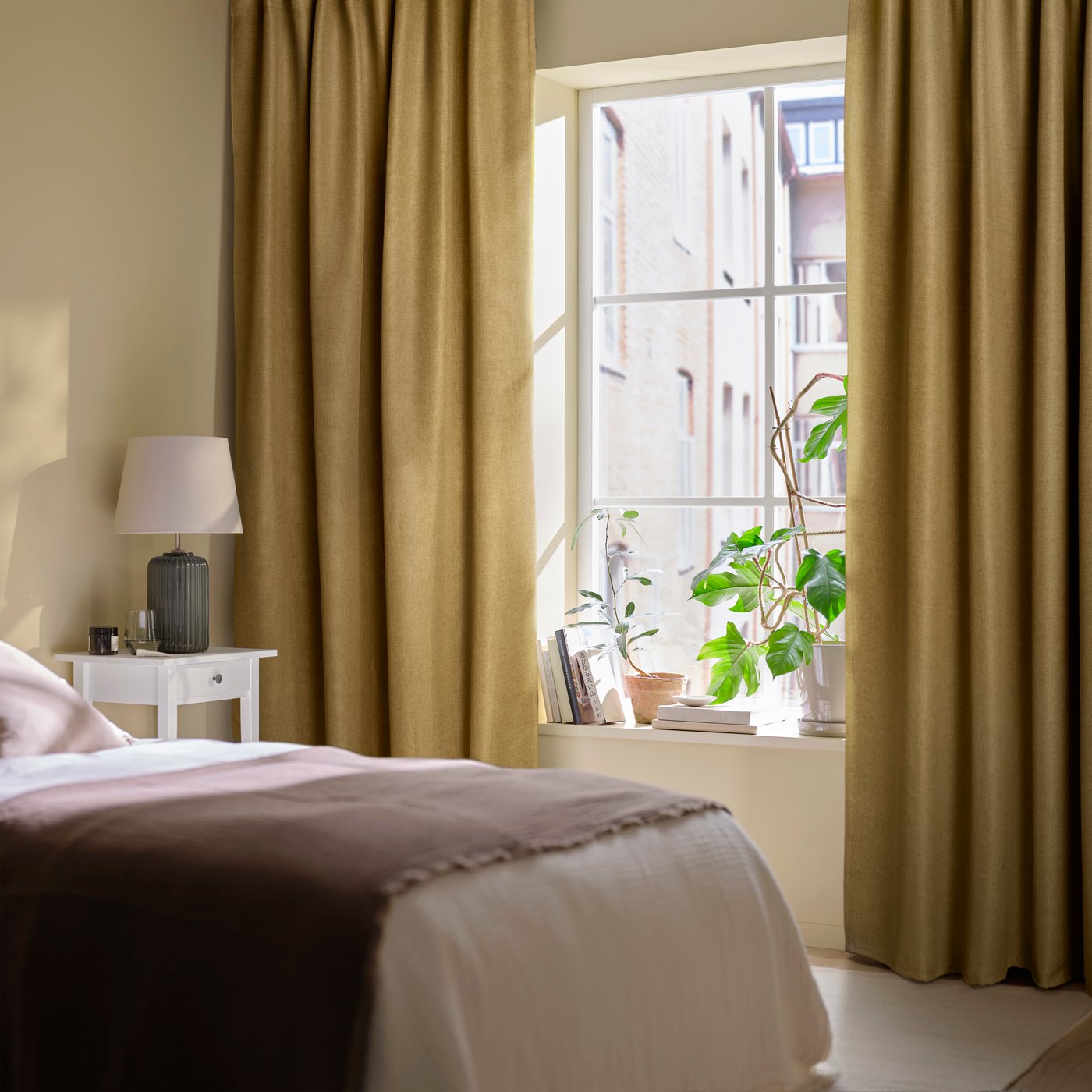 A bedroom with brown ANNAKAJSA curtains.