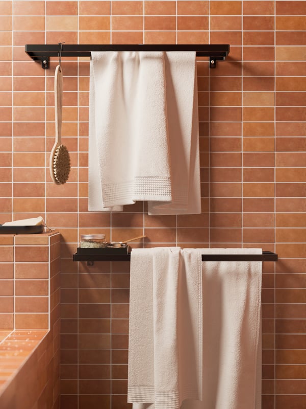 A tiled wall with SKOGSVIKEN towel rails in black, a SKOGSVIKEN tray in black, and VINARN hand towels hanging from the rails.