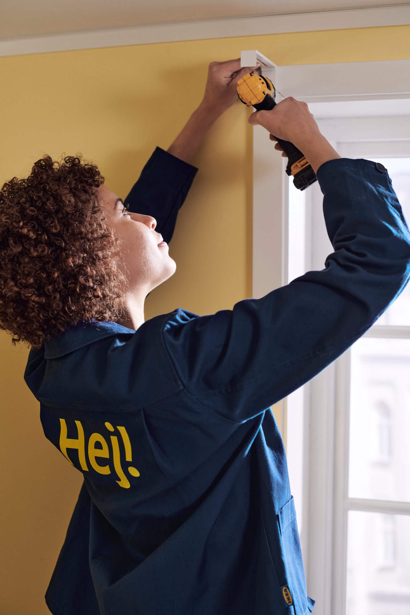 Ein IKEA Mitarbeiter bohrt ein Loch in eine gelbe Wand