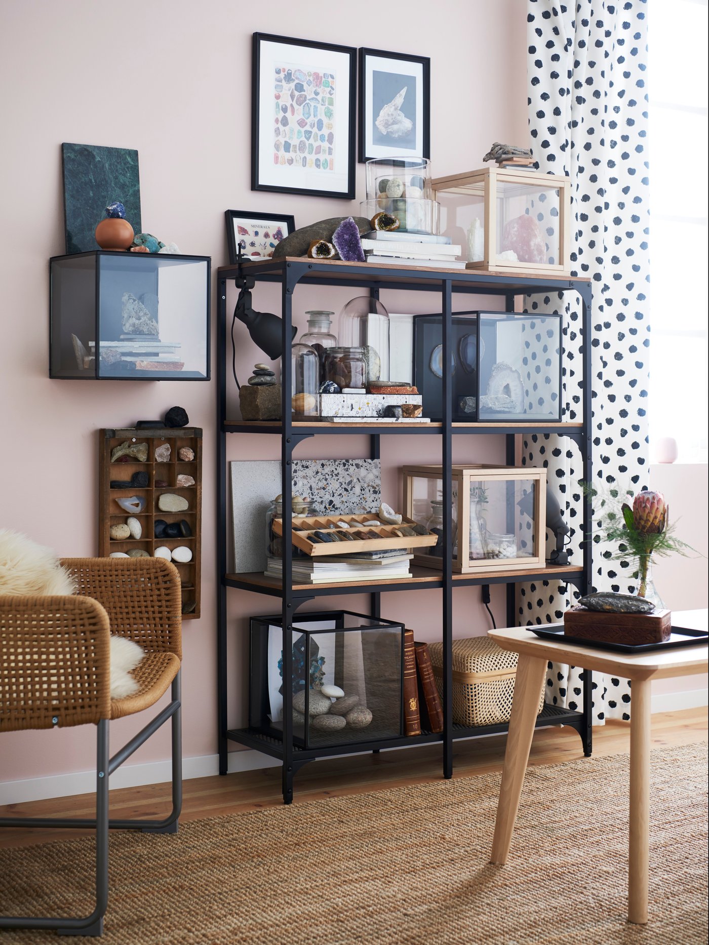 FJÄLLBO black shelving unit in the living room with various decorative items stored on each shelf.