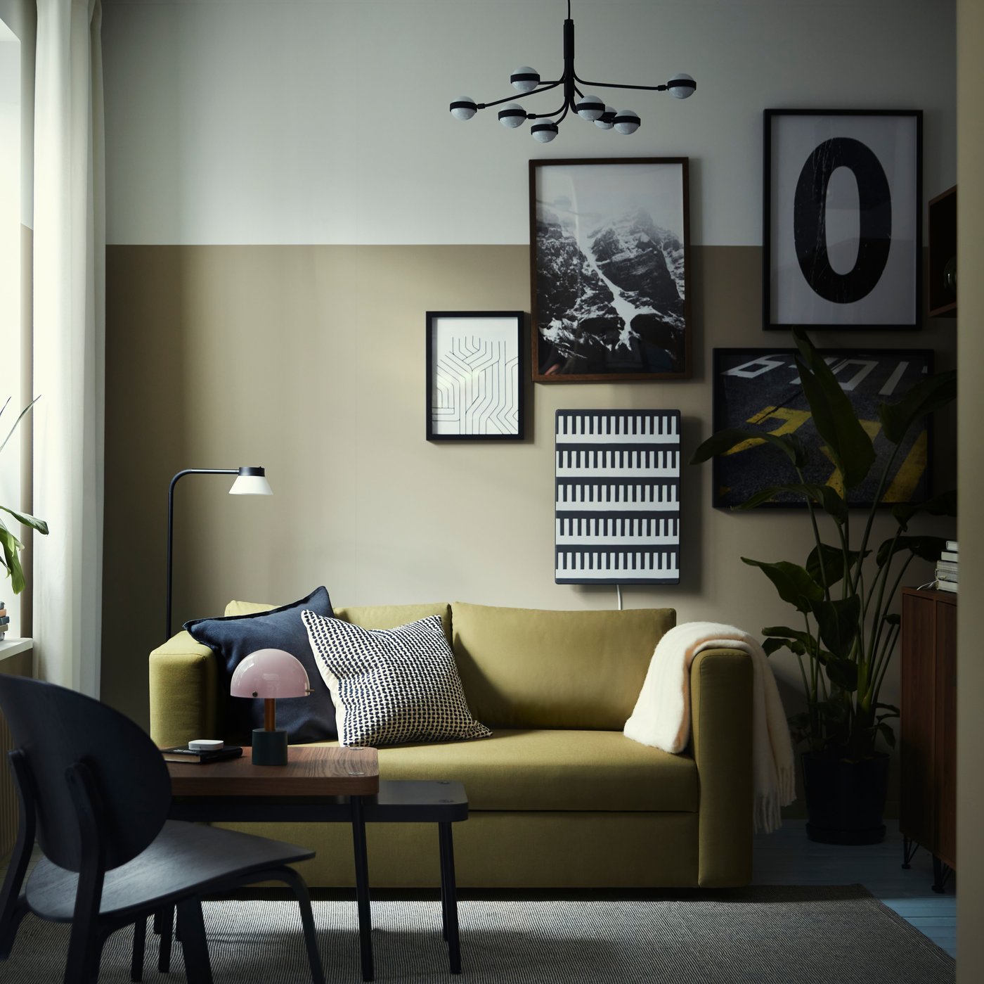 A yellow-green SKÖNABÄCK 2-seat sofa-bed is paired with a black table lamp and pillows in a stylish living room setting.