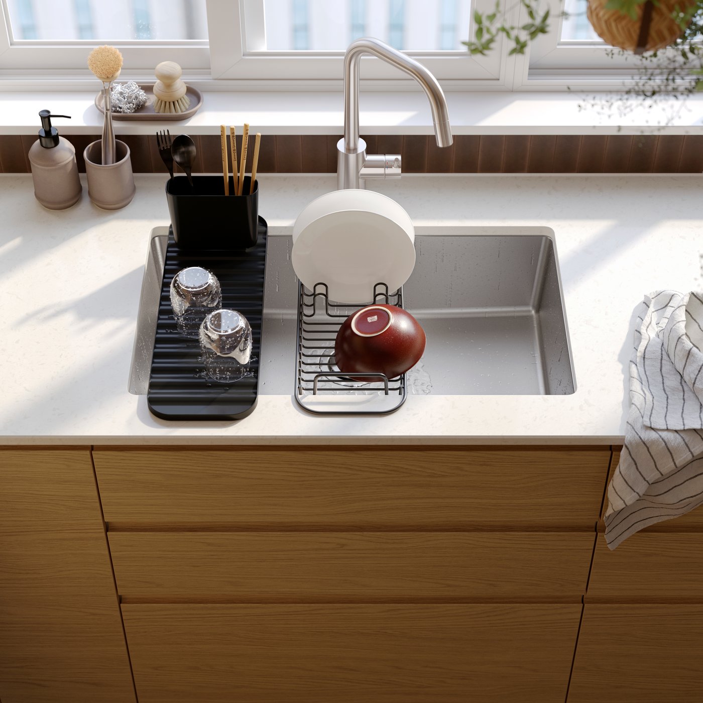 A kitchen sink with a LILLHAVET multifunctional dish rack with items in it and a VRESJÖN inset sink bowl in stainless steel.