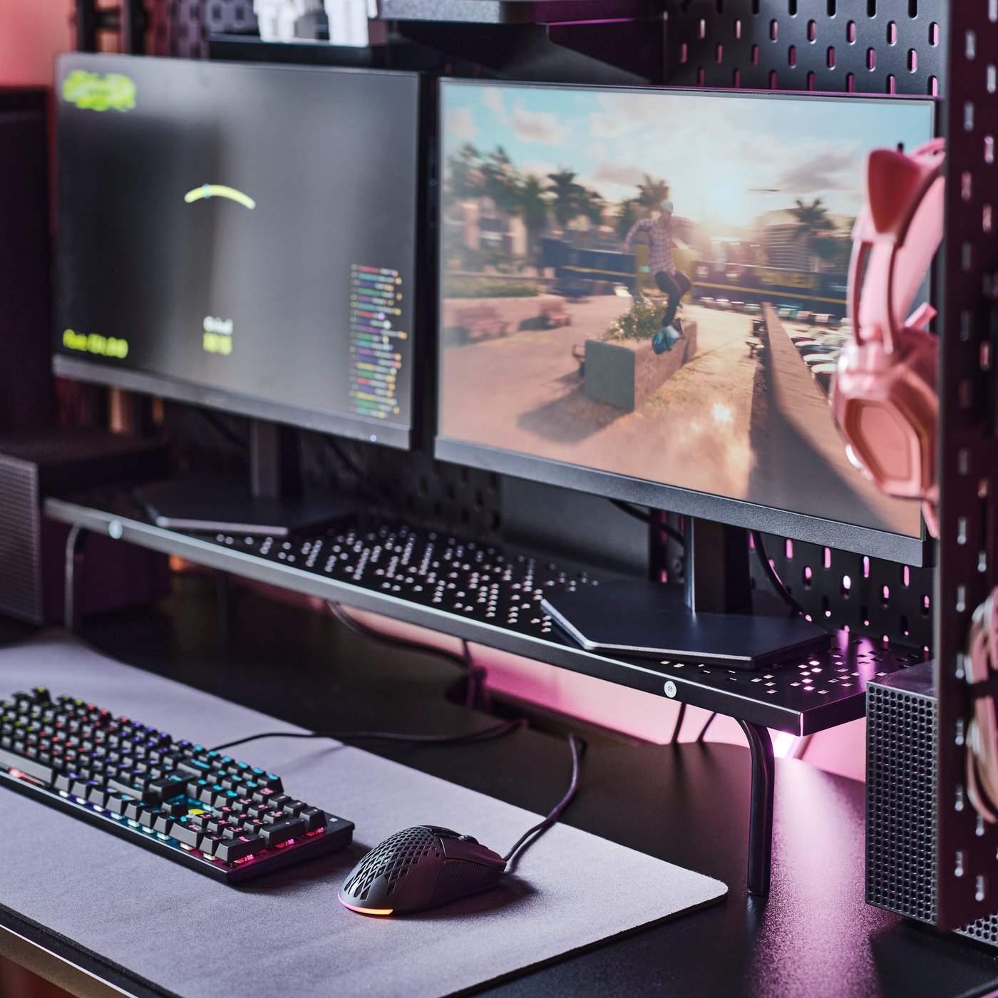 Gejmerska konfiguracija s crnim LÅNESPELARE postoljem za monitor postavljenim ispod dva ekrana, uz tastaturu i miš u blizini.