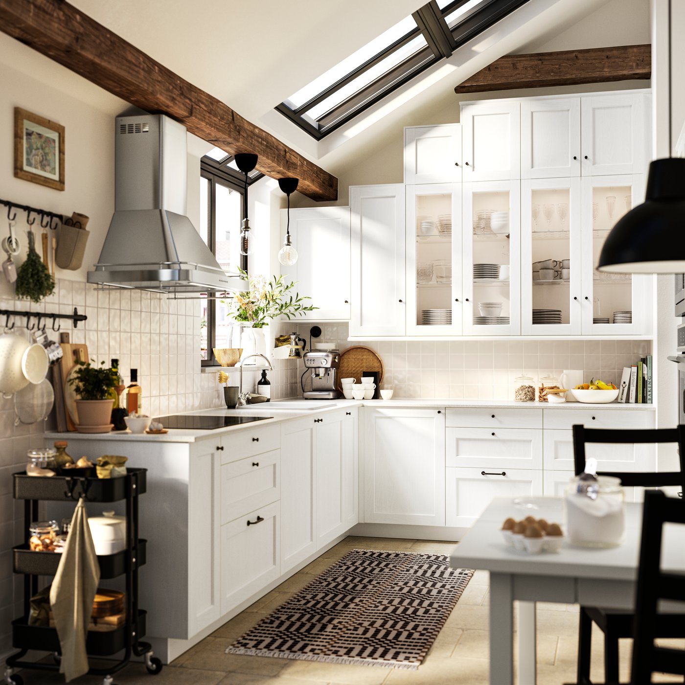 La cocina tiene cajones y armarios colgantes con frentes ENKÖPING blancos y barra HULTARP niquelada con ganchos en la pared.