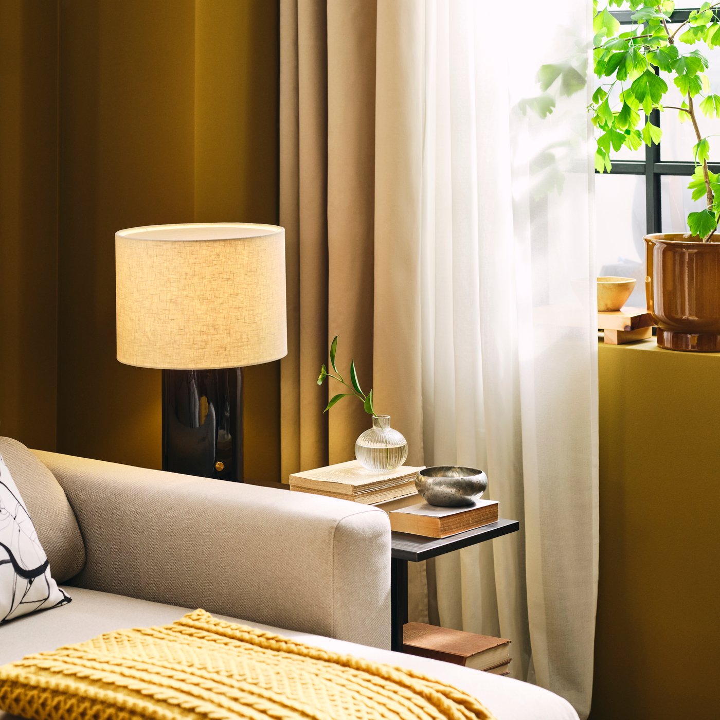 A living room features a light beige MALMKÖPING 3-seat sofa with chaise longue, placed beside a plant and lamps.
