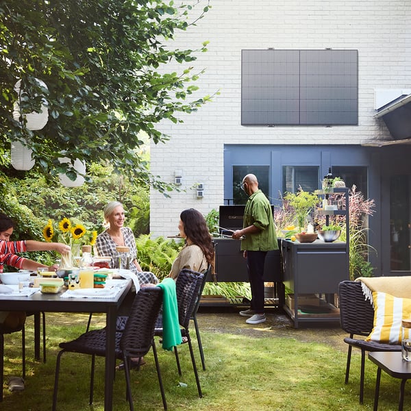 Un jardin avec des tables et des chaises, où les gens sont debout et assis.