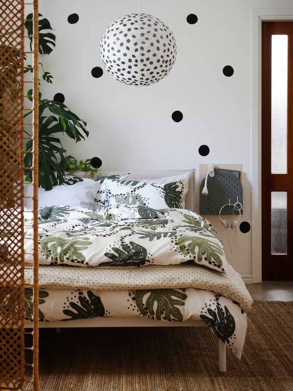 Estructura de cama KLEPPSTAD, blanca, con una funda de plumón con diseñod e hojas de plantas.